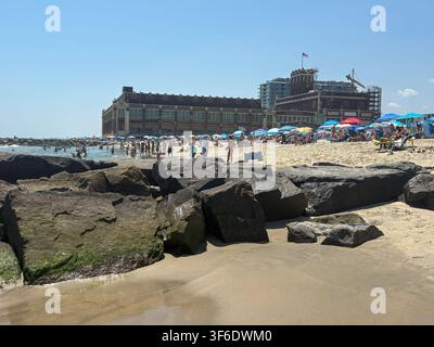 Asbury Park, New Jersey, USA - 26 luglio 2026: Le persone si godono la spiaggia ad Asbury Park con ombrelloni e onde visibili. Foto Stock