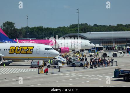 2026.06.25, Cracovia, Polonia: una scena affollata del piazzale aeroportuale con aerei parcheggiati, veicoli di servizio a terra e persone, che mostra aerei metallici Foto Stock