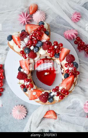 Torta a forma di anello per fidanzamento decorata con bacche fresche e scatola di velluto rosso con anello di diamanti, concetto di proposta di matrimonio Foto Stock