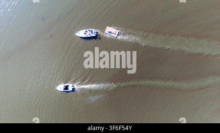 Vista aerea dall'alto di due motoscafi che navigano sull'acqua lasciando lunghe scie Foto Stock