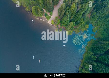 Vista aerea del lago Trillium con surfisti su tavola da remo sull'acqua, una rampa per barche e una fitta foresta sempreverde che circonda la riva nella contea di Clackamas Foto Stock