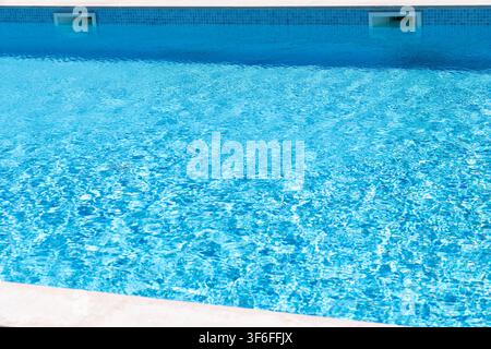 La superficie di una piscina blu brillante riflette la luce del sole, creando schemi scintillanti sulla superficie dell'acqua Foto Stock