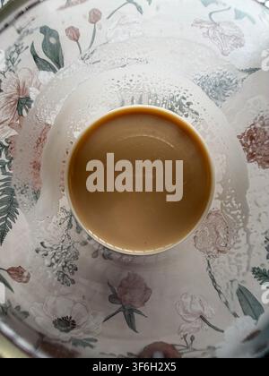 Tazza di caffè latte vista direttamente dall'alto su una tovaglia floreale Foto Stock