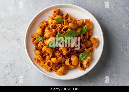 Pasta italiana Pipe Rigate con salsa bolognese e foglie di basilico fresco - Manti makarna Foto Stock