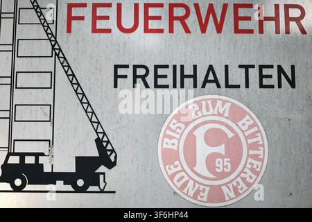 Düsseldorf, Germania, 21.05.2026 Un adesivo con il logo del club Fortuna Düsseldorf è attaccato a un cartello stradale che indica la via di fuga dei vigili del fuoco a Düsseldorf - Mörsenbroich Foto: Norbert Schmidt, Düsseldorf Foto Stock
