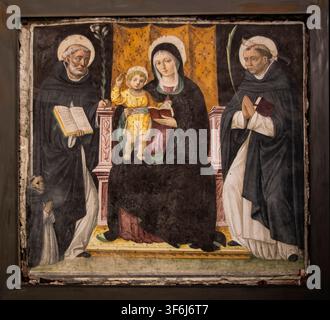 Italia Liguria Genova – Santa Maria di Castello, una delle più antiche chiese della città, si erge sulla collina di Castello sopra i vicoli medievali del centro storico. La sua struttura romanica, i chiostri e la stratificata storia architettonica riflettono il cuore antico del patrimonio religioso e artistico di Genova. – L’affresco della Madonna e del Bambino in trono tra San Domenico e San Pietro Martire, attribuito a Lorenzo Fasolo con probabile collaborazione del figlio Bernardino, risale alla fine del XV–inizio del XVI secolo. L’opera riflette la pittura devozionale raffinata del Rinascimento ligure, combi Foto Stock