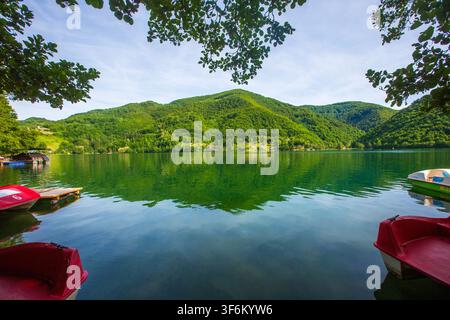 Vista scenica del bellissimo lago di Pliva con montagne boschive verdi e barche a remi rosse a Jajce, Bosnia-Erzegovina Foto Stock