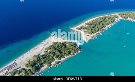 La scena elevata mostra bassi fondi turchesi luminosi attorno a spits sabbiosi e forme di terra densamente vegetate, mentre le barche si radunano vicino alla riva calma della laguna Foto Stock