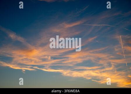 Questa immagine serena cattura una scena naturale mozzafiato con un drammatico intreccio di luce e colore, mostrando vasti cieli pieni di nuvole eteree Foto Stock
