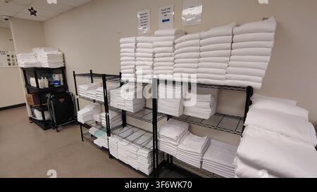 Washington, D.C., USA - 22 marzo 2026: Un magazzino alberghiero con scaffali metallici neri. Pile di asciugamani e lenzuola bianchi puliti sono disposti ordinatamente Foto Stock