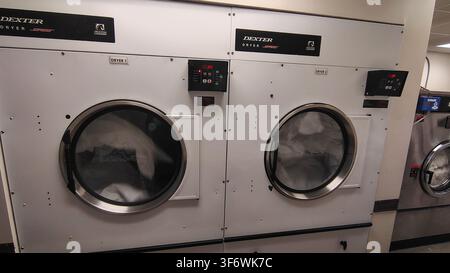 Washington, D.C., USA - 28 settembre 2025: Asciugatrici professionali Dexter in una lavanderia a gettoni o nel locale lavanderia di un hotel. Armadi metallici bianchi con vetro rotondo Foto Stock