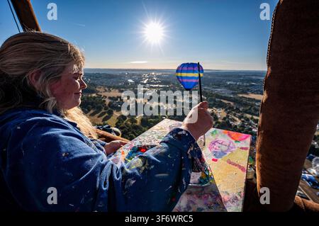 Artista Emily Powell ritratta in un cesto di mongolfiera, dove dipinge dal vivo dall'interno di un cesto di mongolfiera durante la 48a Bristol International Balloon Fiesta, un festival annuale gratuito di mongolfiere, che è il più grande evento del suo genere in Europa. Data della foto: venerdì 7 agosto 2026. Foto Stock