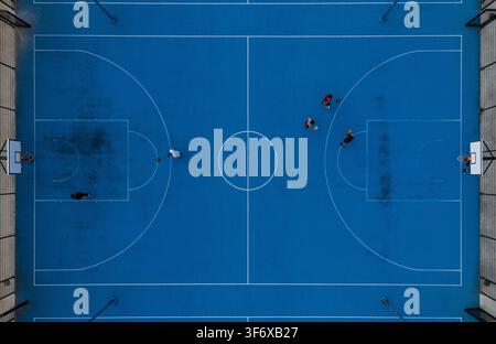 Vista aerea dall'alto di giocatori in competizione su un campo da basket blu completo all'aperto, gioco di basket di strada urbano e concetto sportivo. Foto Stock