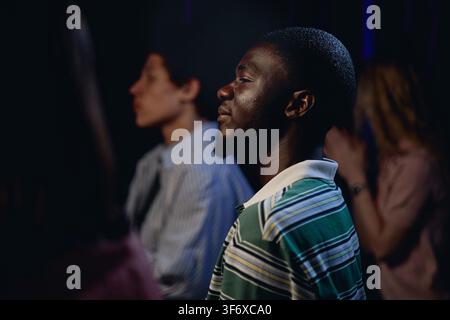 Uomo che guarda una rappresentazione teatrale studentesca in un pubblico buio Foto Stock