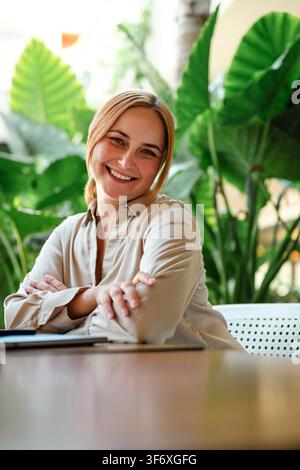 Una donna felice con le braccia incrociate sorride calorosamente Foto Stock