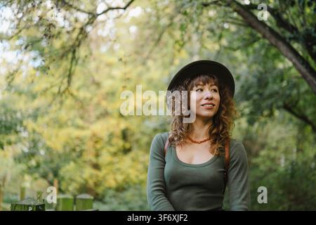 Giovane donna con cappello si gode una tranquilla passeggiata nel bosco Foto Stock
