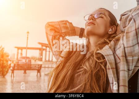 Donna relax tramonto Giovane donna che si rilassa all'aperto con gli occhi chiusi durante una serata al tramonto luminosa mentre indossa le cuffie Foto Stock