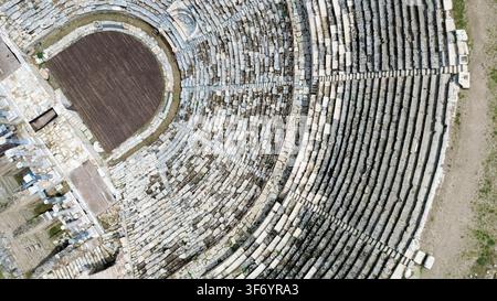 Ripresa aerea ad alta angolazione che cattura l'intricata lavorazione della pietra e la disposizione semicircolare di un anfiteatro romano classico. Perfetto per documentari di viaggio Foto Stock