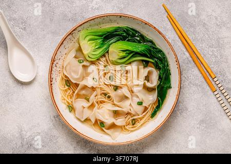 Zuppa calda di noodles con gnocchi (wontons) e cavolo bok choy servita in una ciotola. Foto Stock