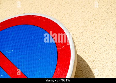 Segnale stradale rosso e blu che mostra le regole del parcheggio attaccato a uno sfondo ruvido Foto Stock