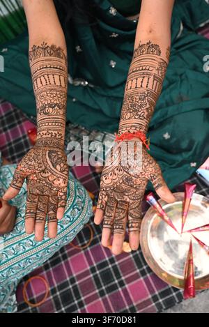 Sposa indiana che mostra un intricato disegno di hennè Mehndi su mani e braccia con filo rosso e coni di Mehndi su Thali del Bengala Occidentale Foto Stock