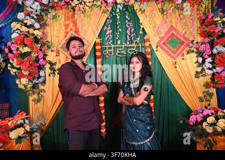 Giovane coppia indiana che posa insieme, sposa indiana in saree blu con mehndi e uomo in camicia marrone durante la decorazione della cerimonia mehndi Foto Stock