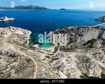 Vista aerea della Calanque de Saint-Esteve sulle isole Frioul con acque turchesi, scogliere rocciose e una piccola spiaggia a Marsiglia, Provenza-Alpi- Foto Stock