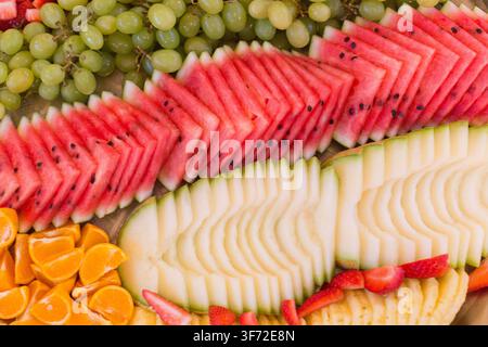 Un vivace piatto di frutta con melone, uva, anguria e arance servito a un evento catered. La location e il punto di riferimento non sono identificati. Foto Stock