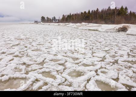 Vista aerea del faro di Sturgeon Point circondato da banchi di ghiaccio e acqua ghiacciata sul lago Huron a Harrisville, Michigan, Stati Uniti. Foto Stock