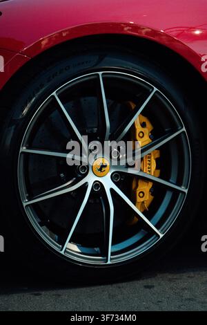 Primo piano di un cerchione in lega di un'auto sportiva di lusso con logo badge Ferrari al centro e pinza dei freni gialla Foto Stock