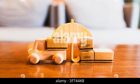 Camion giocattolo di legno con scatole di cartone e simbolo di ombrello sul tavolo, che rappresenta la protezione dei pacchi, il servizio di consegna e la spedizione sicura nella logistica Foto Stock