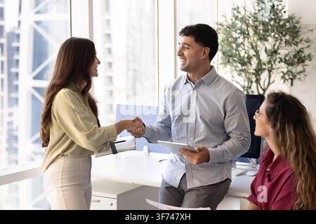 Colleghi diversi che si stringono la mano durante un incontro collaborativo in un coworking Foto Stock