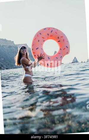 Donna, mare, ciambella, giovane donna felice che tiene una ciambella gonfiabile nell'acqua dell'oceano durante le vacanze estive Foto Stock
