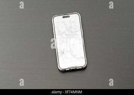 Smartphone che mostra la mappa della regione di Madrid, appoggiato su una superficie di legno scuro Foto Stock