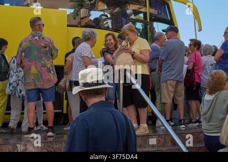 Gran Canaria, Spagna – 8 agosto 2026: Un gruppo di turisti anziani in fila per salire su un pullman giallo per un tour guidato, catturando i viaggi di gruppo Foto Stock