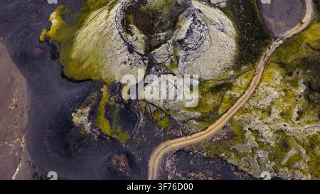Prospettiva a droni di un paesaggio geotermico islandese con depositi minerali chiari, vegetazione di muschio, canali d'acqua scura e Foto Stock