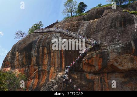 Sigiriya, o il Roccia del Leone, nello Sri Lanka – Le persone salgono e scendono la ripida scala di metallo che conduce alle rovine del palazzo in cima a Sigiriya Foto Stock