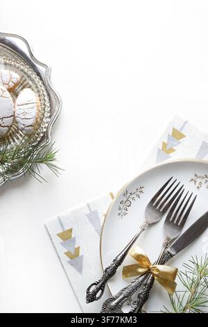 Elegante esposizione da tavolo per le feste con biscotti italiani su vassoio d'argento, posate vintage con nastro dorato e decorazioni di pino. Spazio per copia. Foto Stock