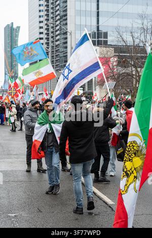Toronto, Ontario - 14 febbraio 2026: Raduno della diaspora iraniana con bandiere su Yonge Foto Stock
