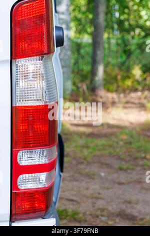 Prima verticale del fanale posteriore di un camper bianco parcheggiato in un campeggio boschivo in Finlandia. Foto Stock