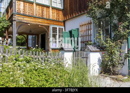 Giardino anteriore idilliaco con cancello e decorazione scolpita sulla facciata dell'edificio residenziale, Altaussee, Stiria, Austria Foto Stock