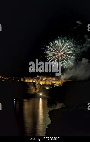 Fuochi d'artificio che esplodono nel cielo notturno sopra Bonifacio, Francia, riflettendosi sul Mar Mediterraneo, Bonifacio, Corsica, Francia Foto Stock