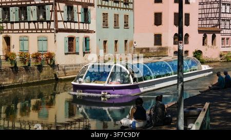 STRASBOURG, FRANCIA - 6 AGOSTO 2026 - Turisti che si godono una gita in barca lungo il canale passando davanti a case storiche in legno a Strasburgo, Francia Foto Stock