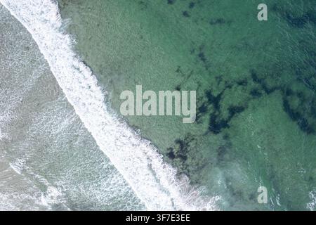 Vista dall'alto delle onde del mare che si infrangono dolcemente su una costa sabbiosa Foto Stock