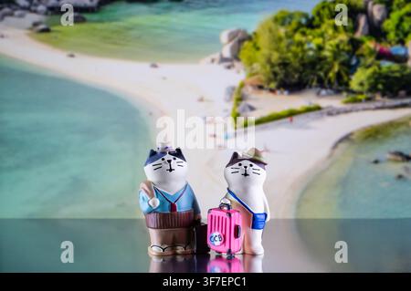 Chiang Mai, Thailandia - 07 agosto 2026 : Due figure di gatti viaggiatori stravaganti con bagagli su uno sfondo della spiaggia aerea di Koh Nang Yuan Foto Stock