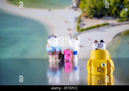 Chiang Mai, Thailandia - 07 agosto 2026 : Stravagante statuetta di gatto che sbircia da uno zaino giallo sullo sfondo della spiaggia di Koh Nang Yuan Foto Stock