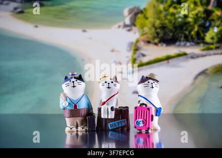 Chiang Mai, Thailandia - 07 agosto 2026: Tre figurine di gatti viaggiatori stravaganti con bagagli su uno sfondo di spiaggia aerea di Koh Nang Yuan Foto Stock