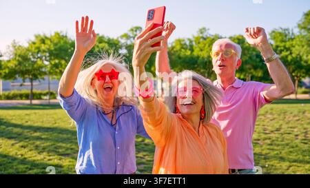 Amici anziani si divertono a scattare un selfie di gruppo nel parco Foto Stock