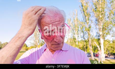 Uomo anziano con occhiali da sole a forma di cuore nel parco Foto Stock