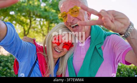 Coppia di anziani che si gode un selfie divertente con il segno della pace o della V Foto Stock
